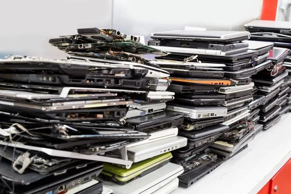 Stack of old, disassembled laptops on table for IT Asset Management Software through Titan-8