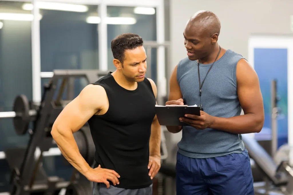 Trainer speaking with client, at gym where they track certifications and contracts to stay compliant.