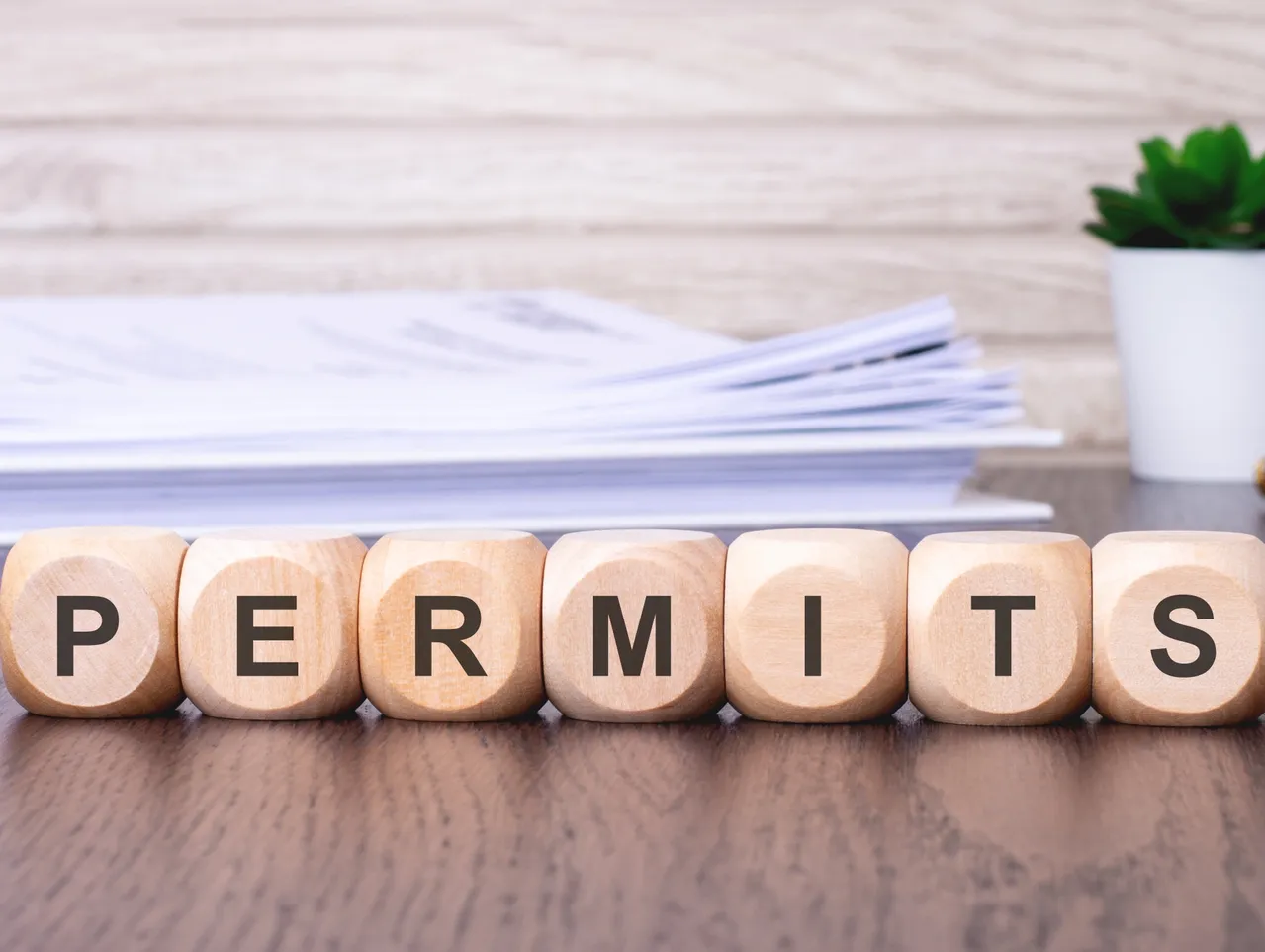 Wooden cubes on a desk spelling the word permit, symbolizing permit tracking software