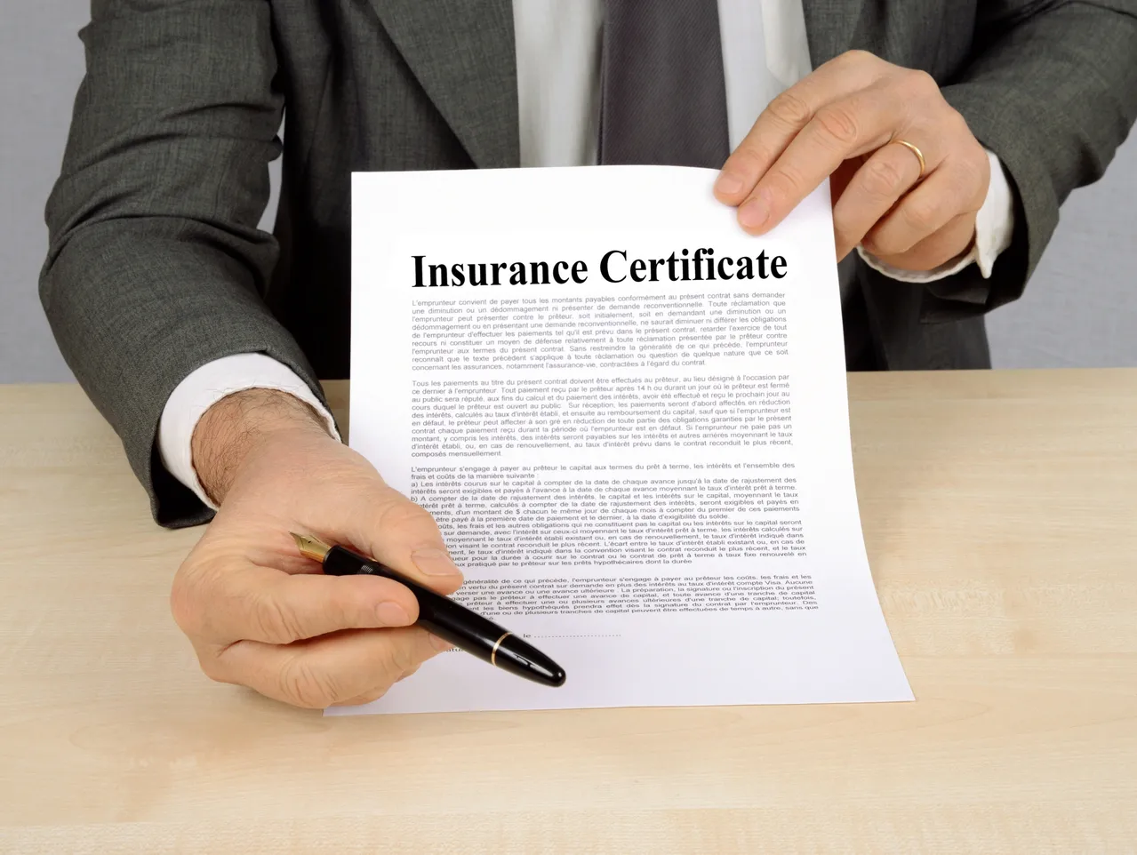 Man holding insurance certificate and pen for insurance compliance tracking