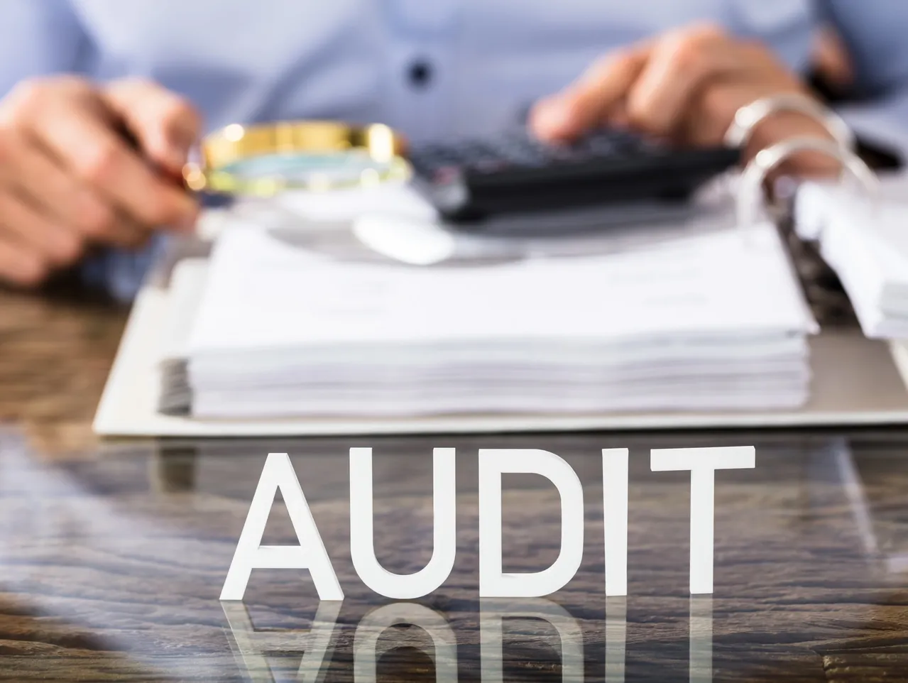 Audit text with documents and magnifying glass representing workers’ comp audits and HR compliance