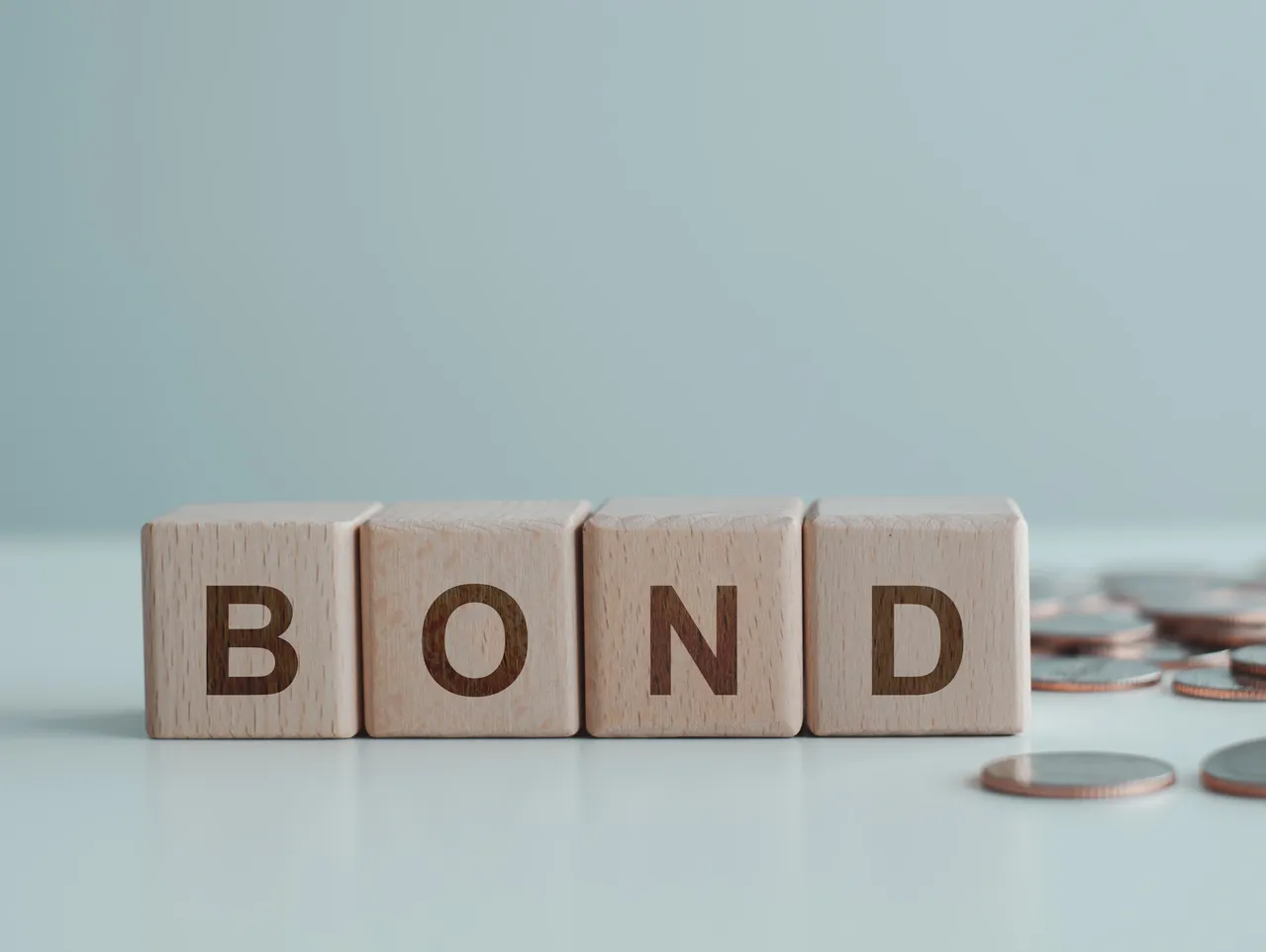 Wooden blocks spelling "BOND" with coins.