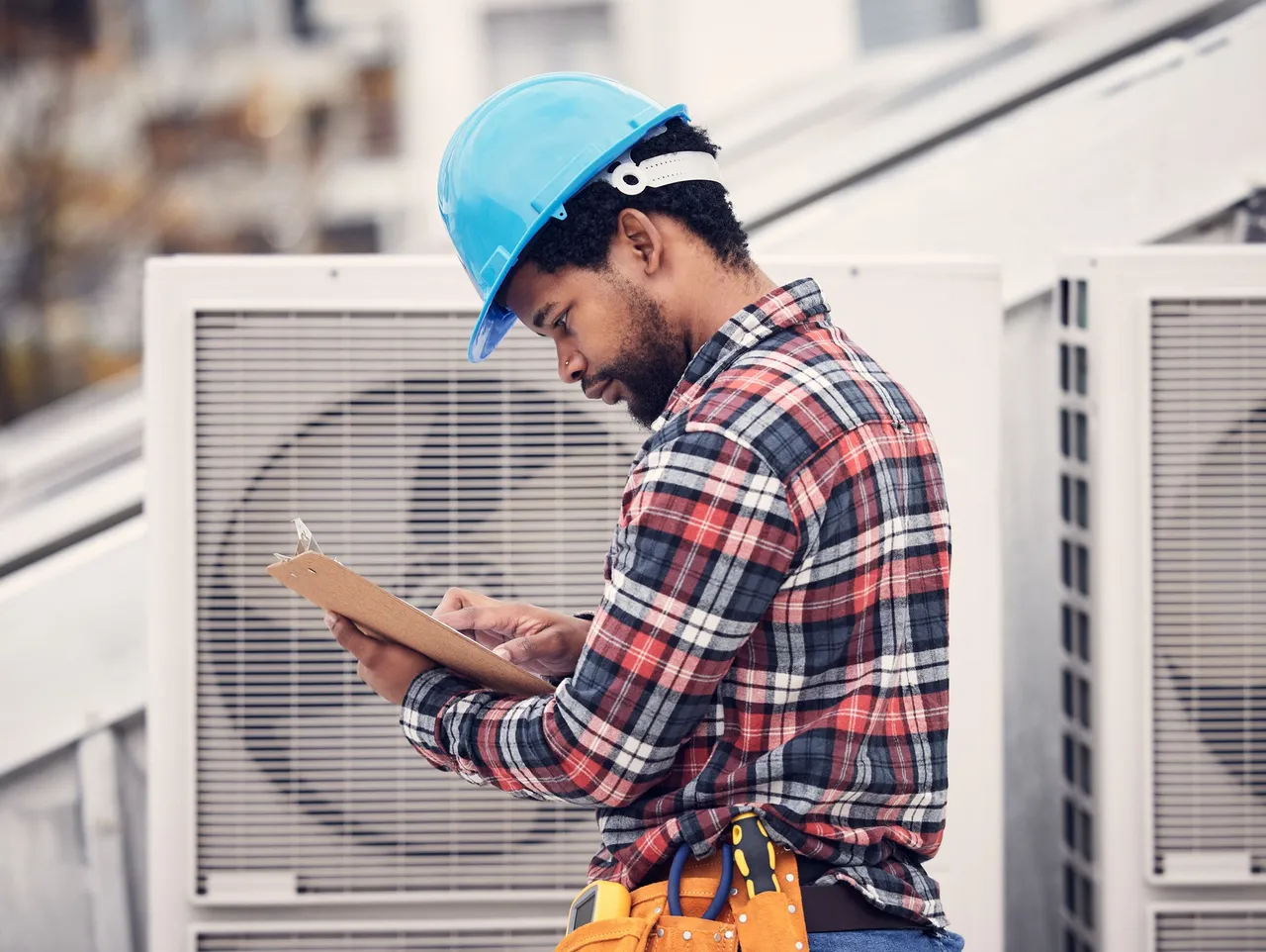 Technician on roof inspecting HVAC unit for preventive maintenance