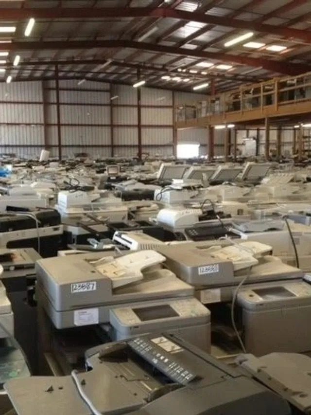 Warehouse full of copiers staged for deployment, illustrating efficient copier lease management.