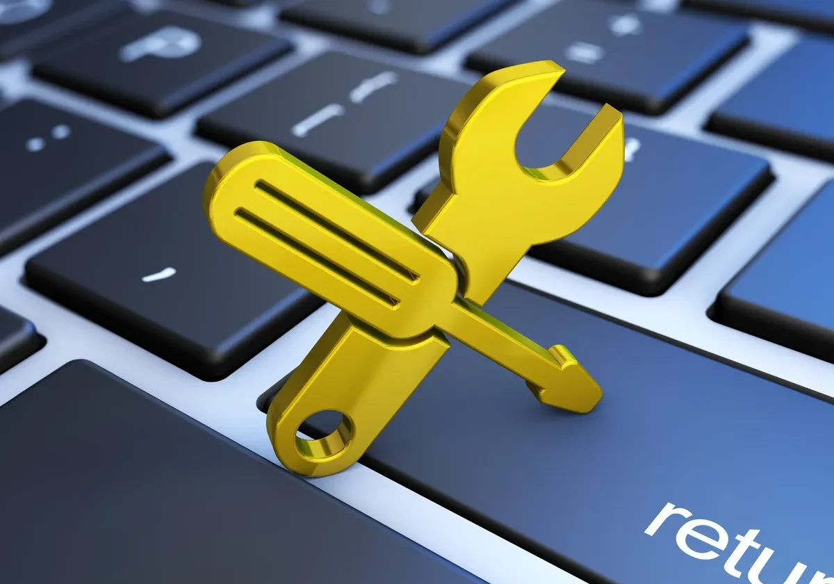 Wrench and screwdriver icon over a computer keyboard, symbolizing RenewAlert as a copier lease management tool for simplifying employee tasks
